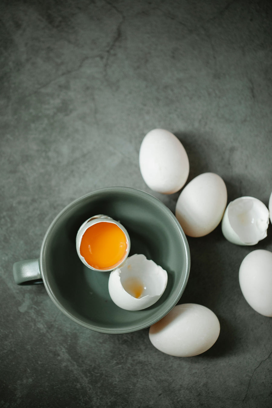 Eggs and cracked shells beside a ceramic bowl, a food source of biotin for hair, skin and nails