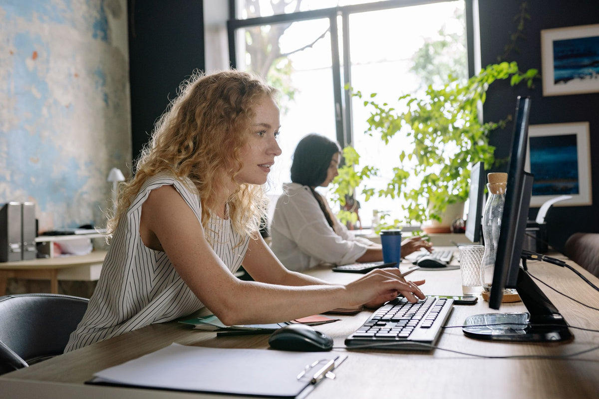 Two people focused at their desks in a bright office, measuring cognitive performance at work