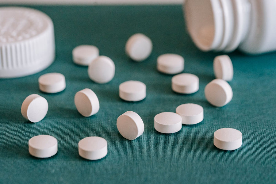 White tablets spilling onto a green surface, the problem with ingredient first supplements