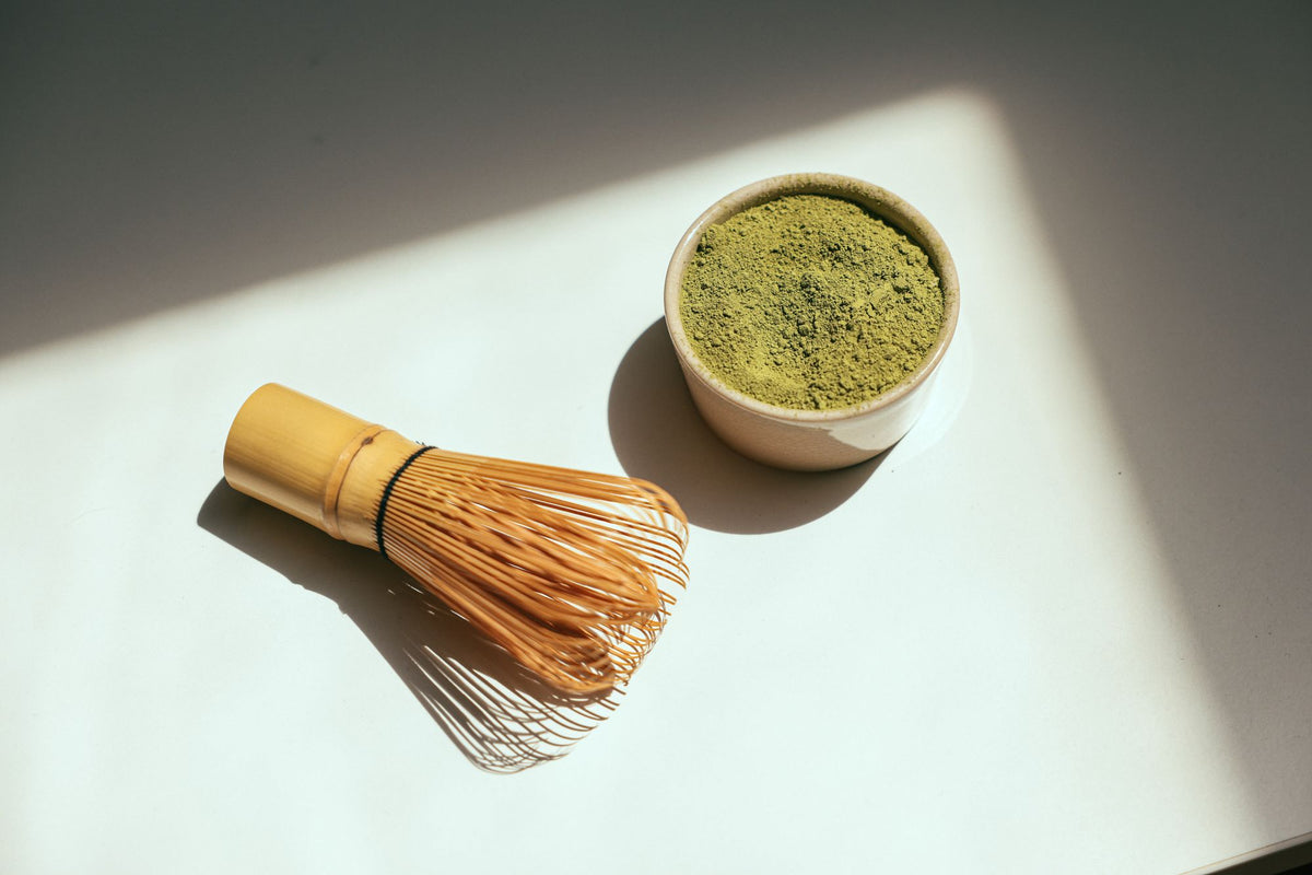 Matcha powder and bamboo whisk in sunlight, a natural source of L theanine
