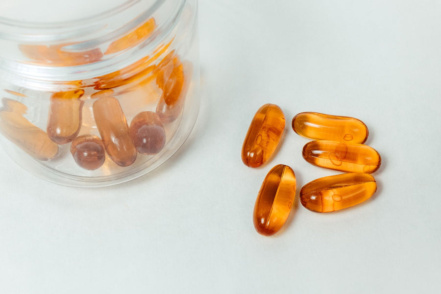 Amber vitamin capsules spilling from a glass jar, showing which vitamins benefit from liposomal delivery