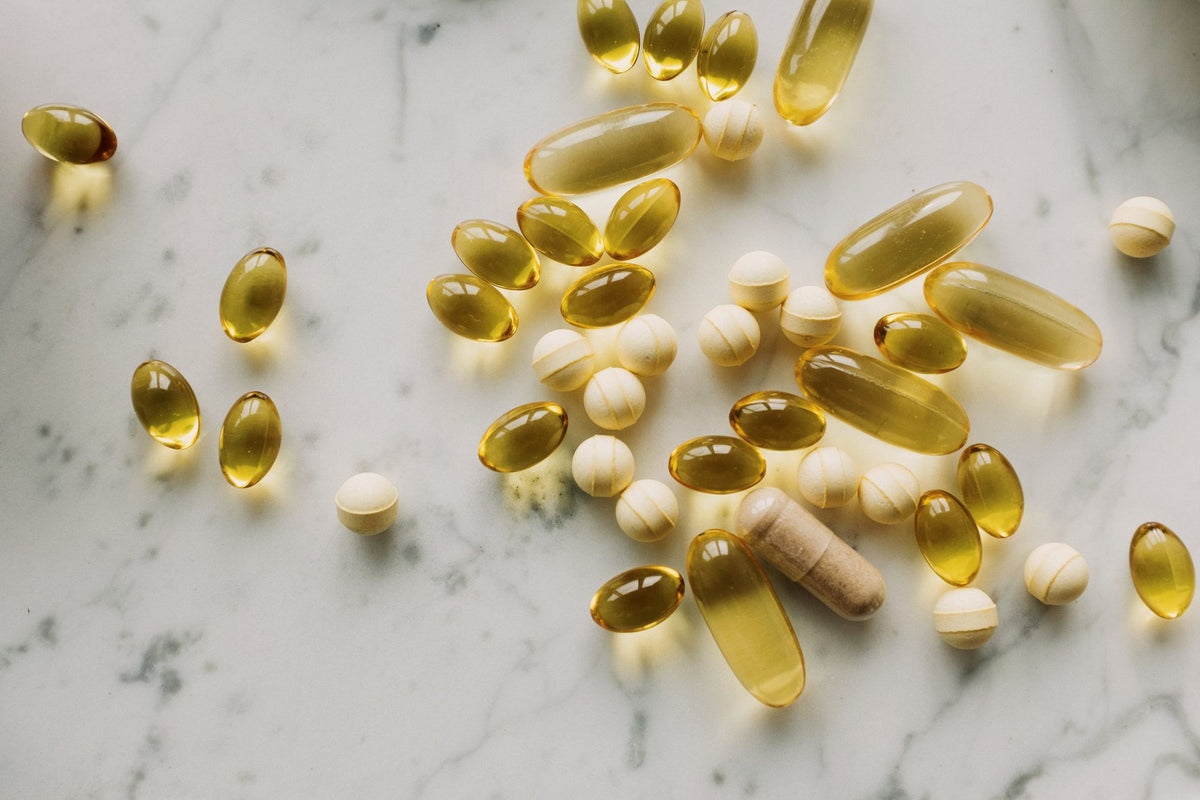 Capsules and softgels on light marble, comparing liposomal and traditional supplements