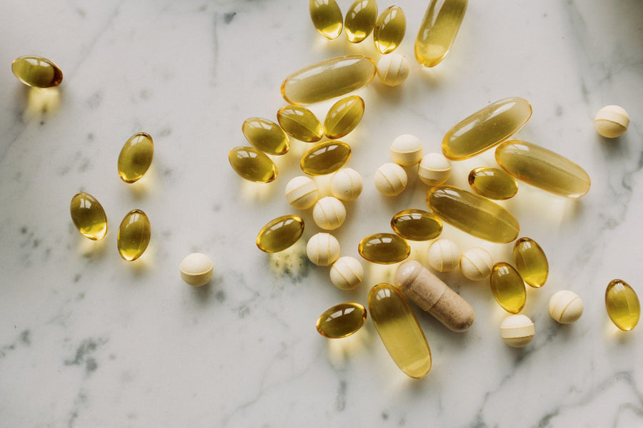 Capsules and softgels on light marble, comparing liposomal and traditional supplements
