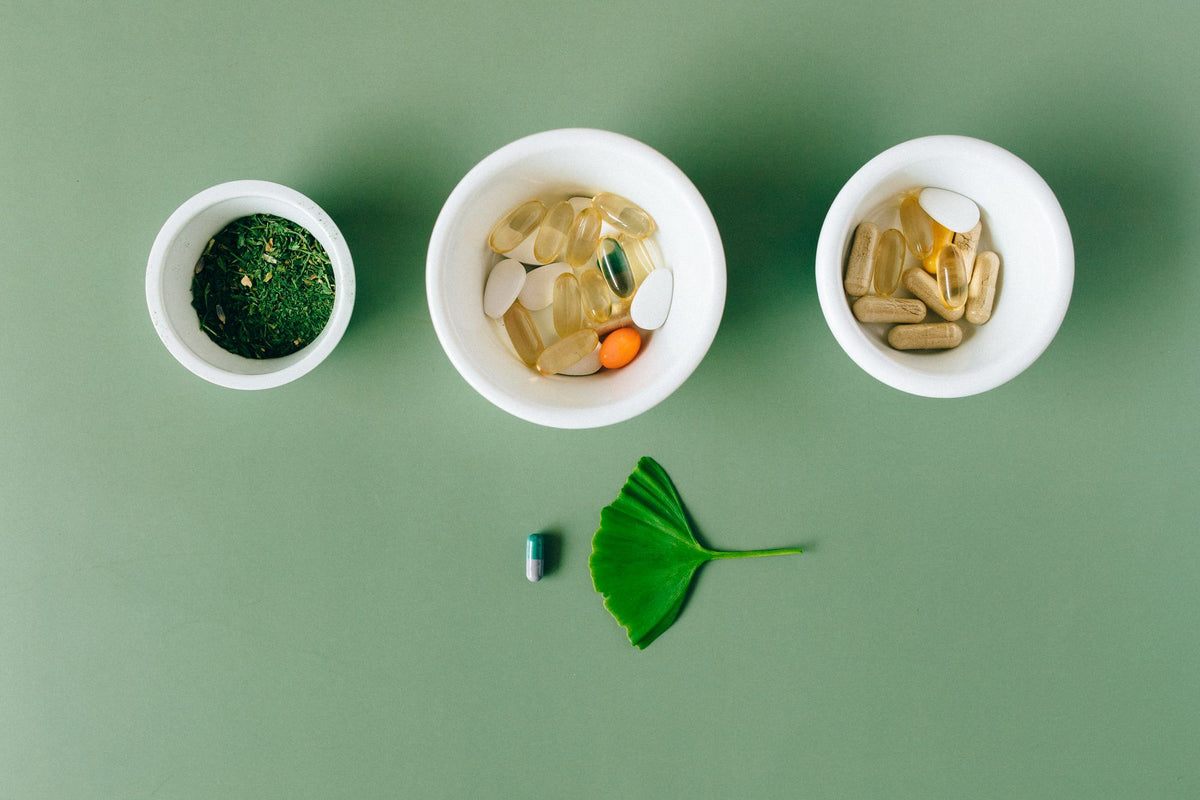 Capsules and herbs in ceramic bowls, daily multivitamins for energy and immunity